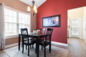 A stylish dining area featuring a red accent wall, black furniture, and modern decor.